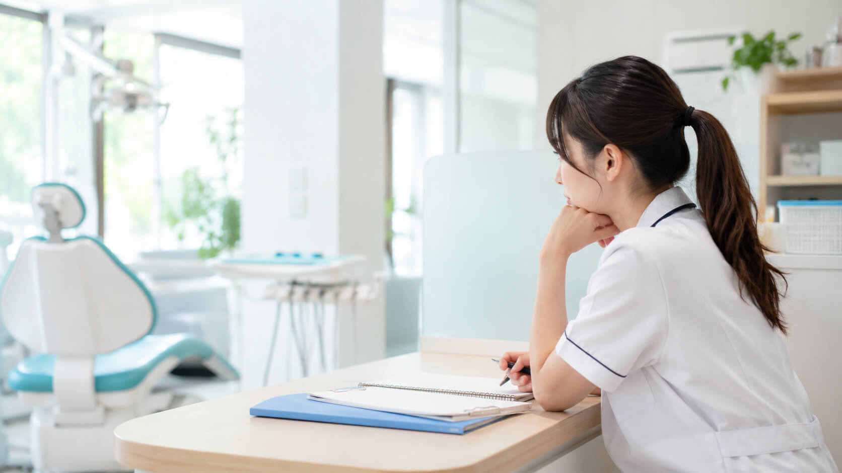 歯科医院内で職場環境について考える若い歯科衛生士の様子