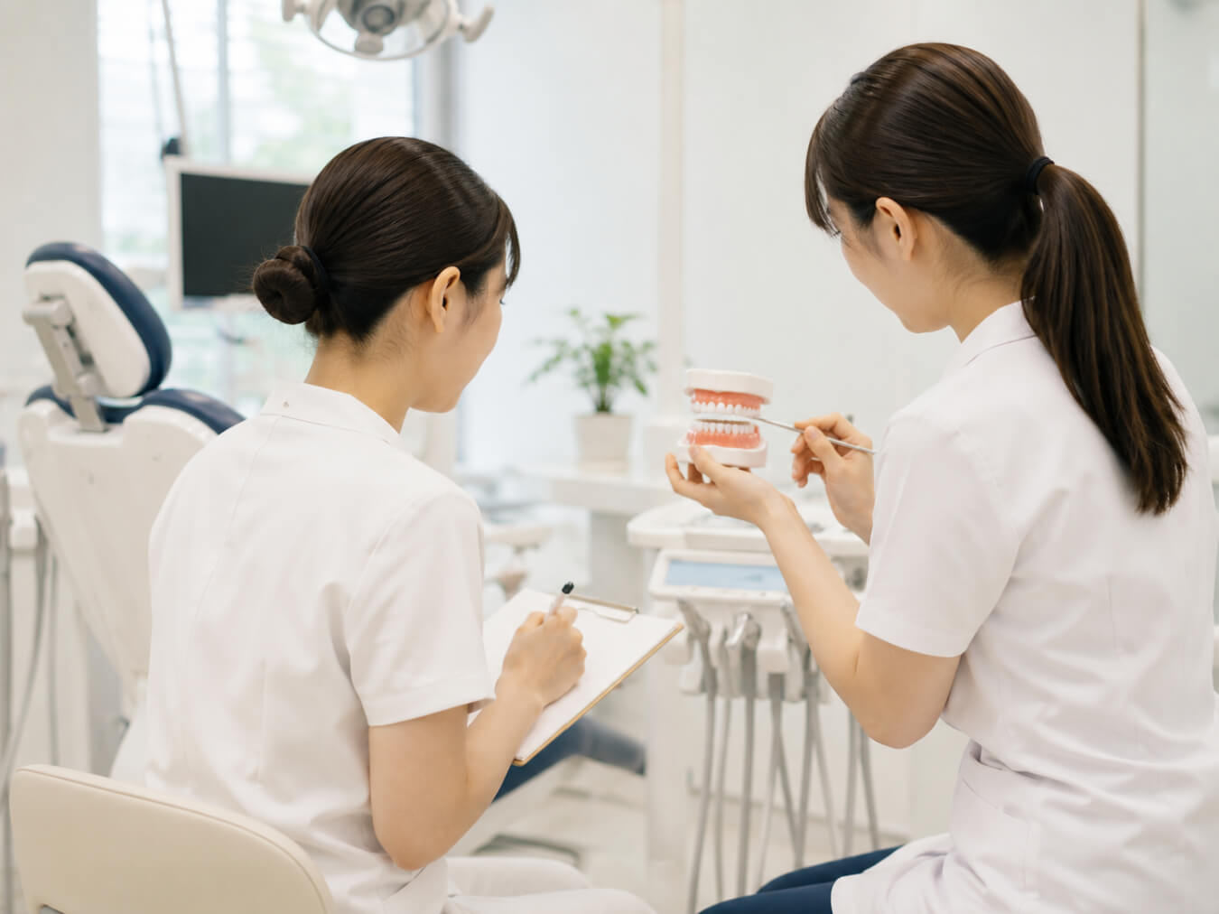 歯科医院で先輩から指導を受ける新人スタッフの様子